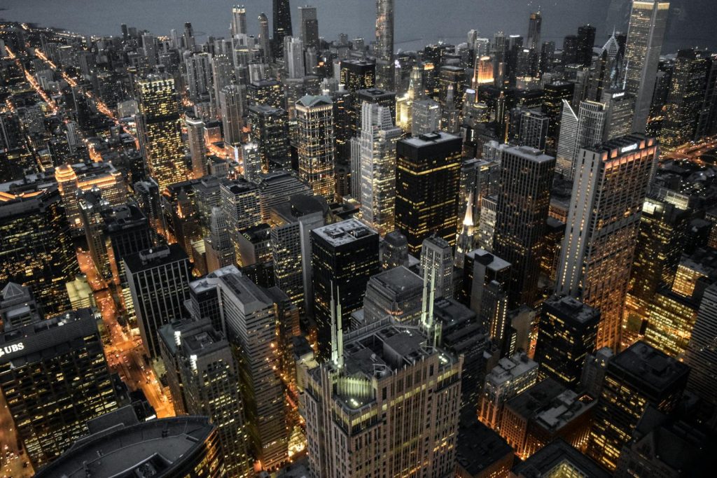Illuminated skyscrapers and bustling urban life symbolizing decentralized power of avoiding the societal cost of corporate comfort.