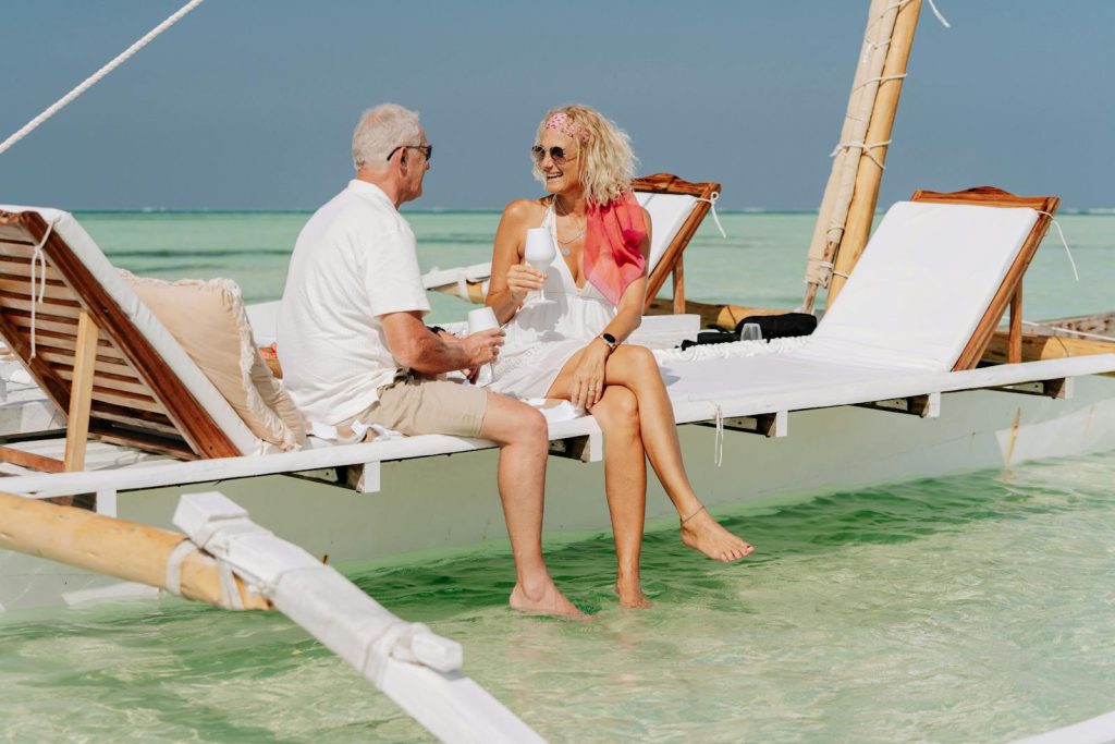 Elderly couple on a dhow enjoying a sunny beach day after successfully escaping the pension trap.