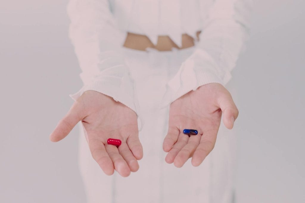Close-up of hands holding red and blue pills, symbolizing the choice of leveraging corporate skills.